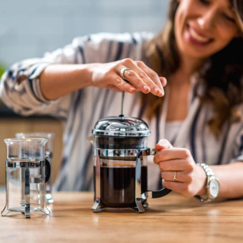  woman using a french press to make coffee